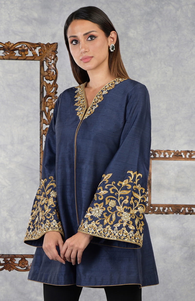 A woman models a navy blue raw silk jacket with gold embroidery on the neckline and sleeves.