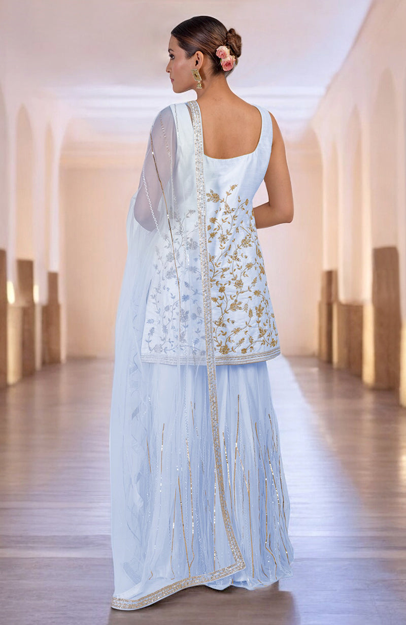 A woman models an ice blue hand-embroidered sharara set with gold and silver details.