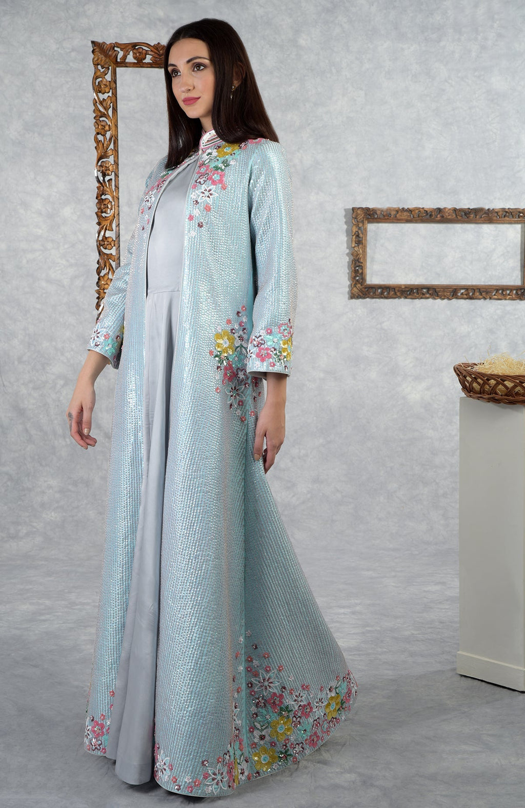 A woman models an aqua-grey sequin hand-embroidered jacket set with floral details.