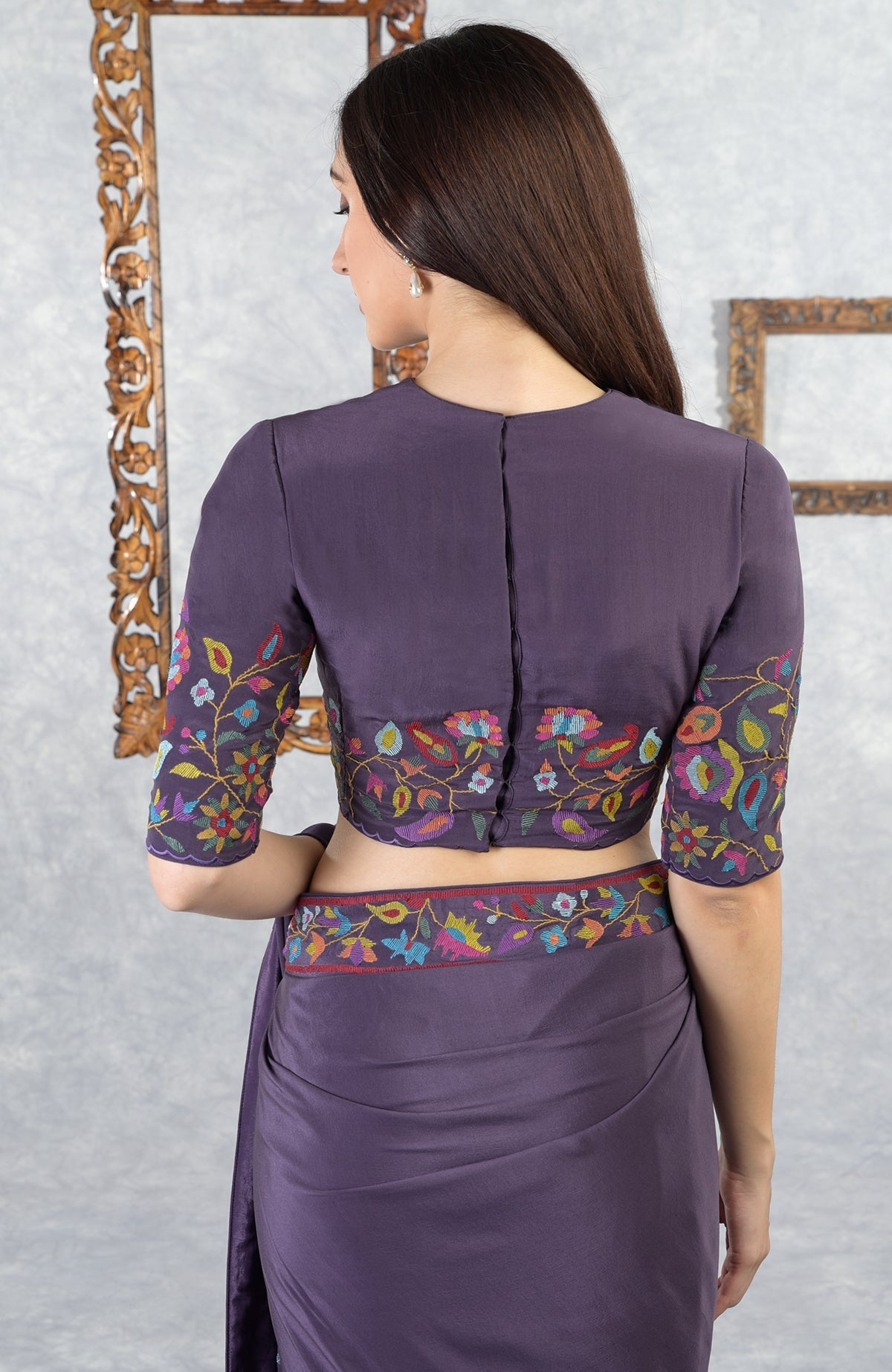 A woman from behind wears an eclipse-colored saree with colorful floral embroidery.