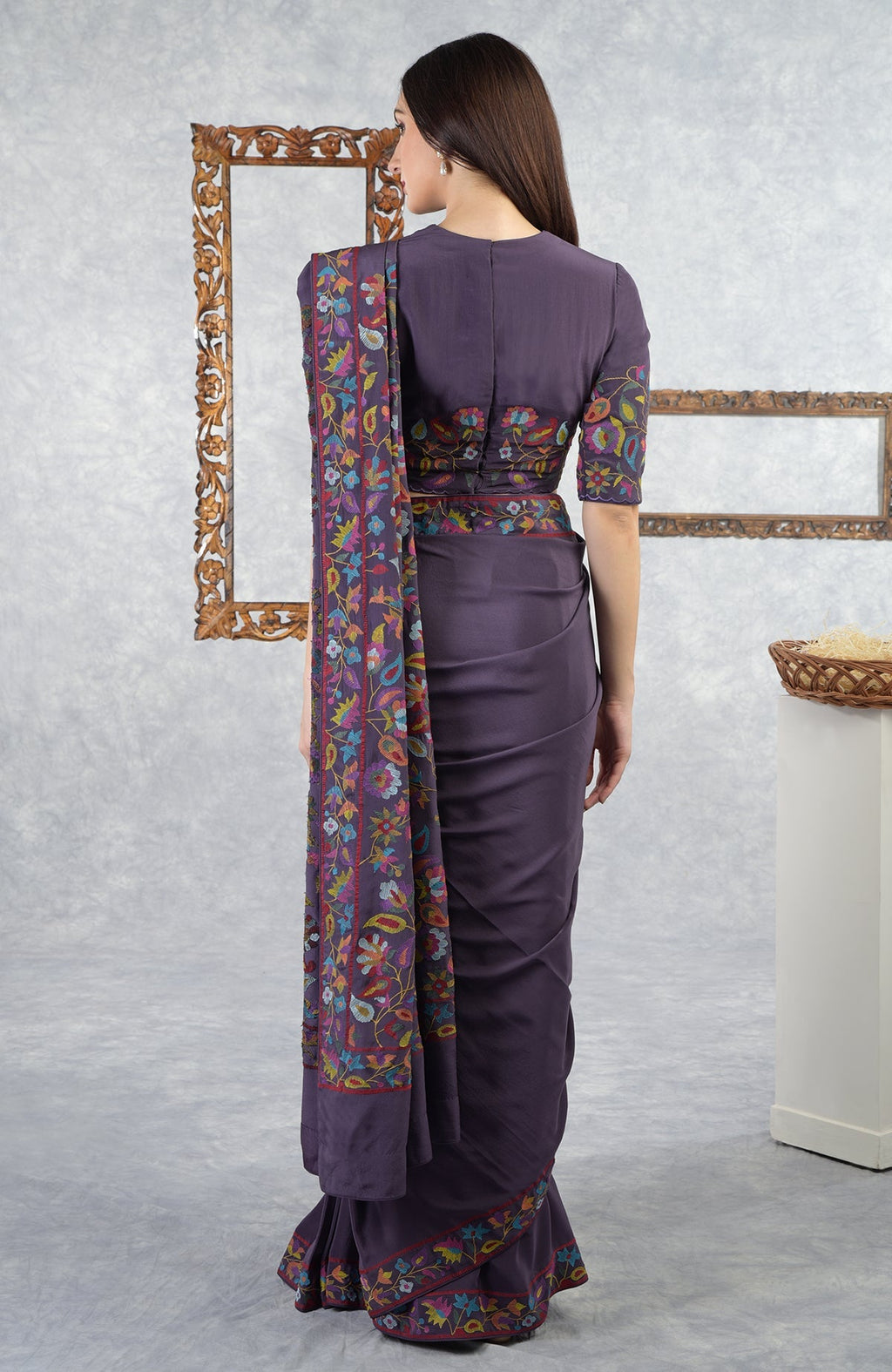 Woman in an eclipse-colored saree with multi-color floral Kani art embroidery.