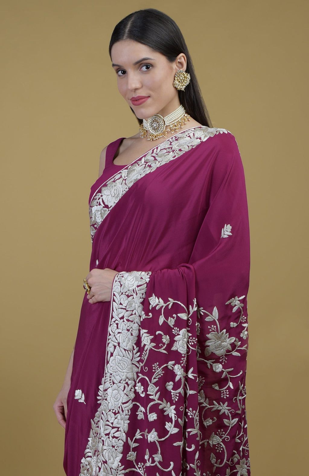 A woman models a peacock pink Parsi Gara hand-embroidered saree with ivory floral patterns.