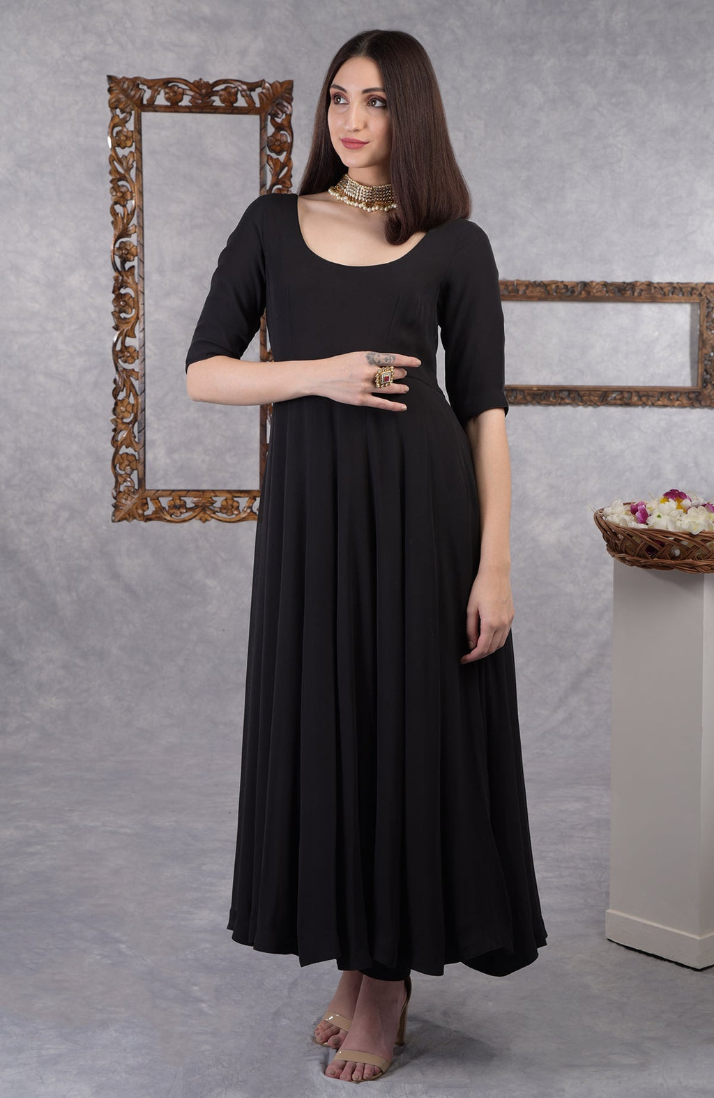 A woman in a black pure georgette Anarkali set with a gold choker and ring.