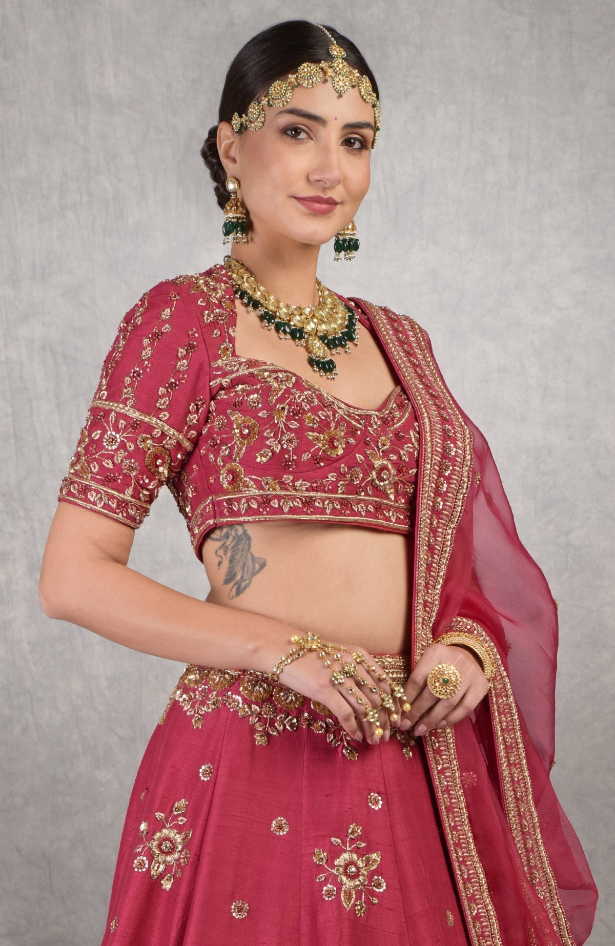 Red raw silk blouse with gold zardozi hand embroidery and floral motifs on sleeves.