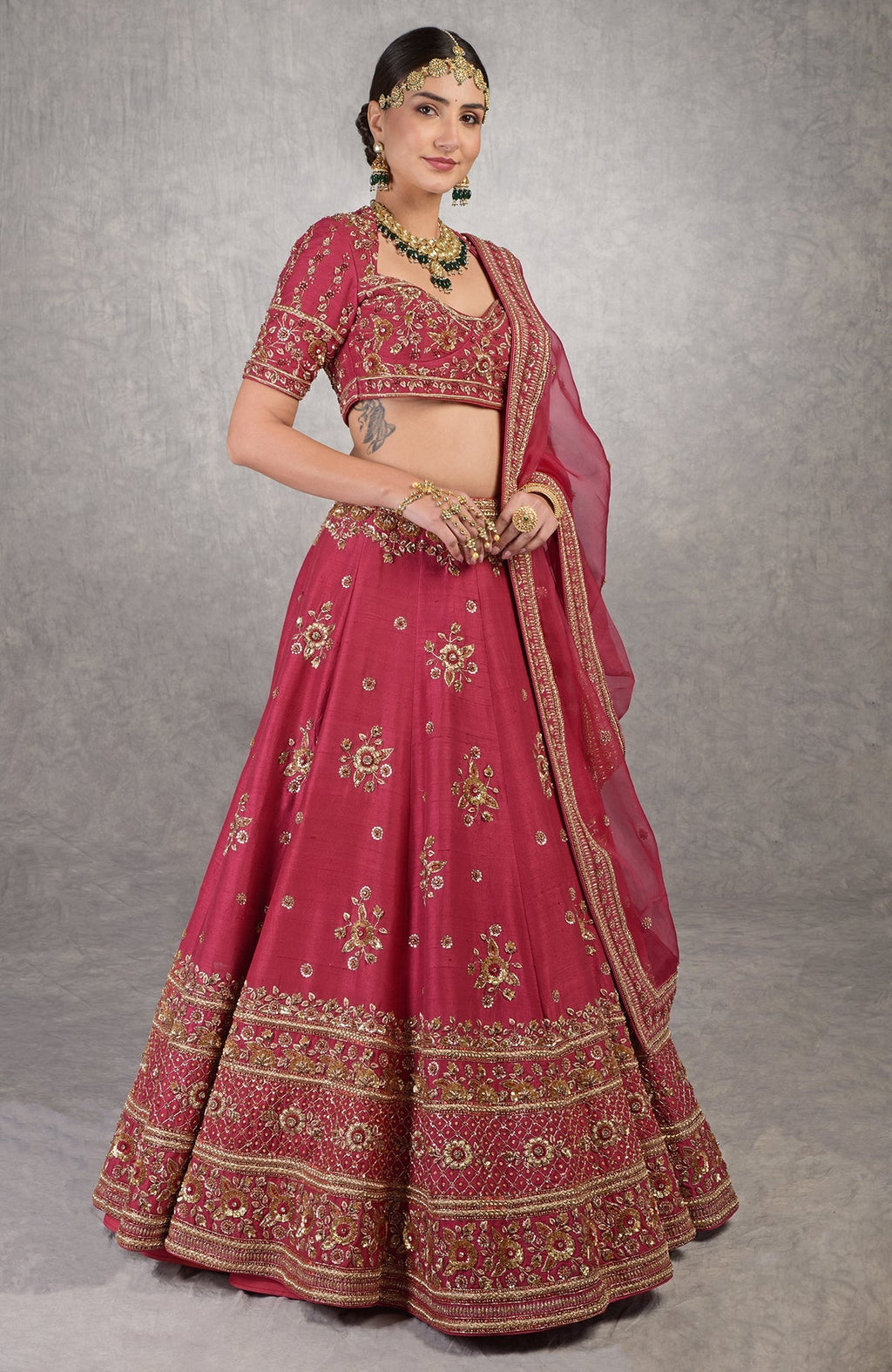 Deep red lehenga set with gold zardozi embroidery and floral motifs on raw silk fabric.