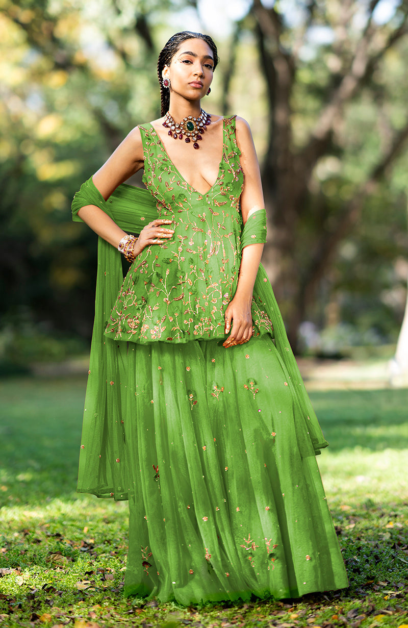 A woman models a green floral embroidered sharara set with a deep V-neck top.