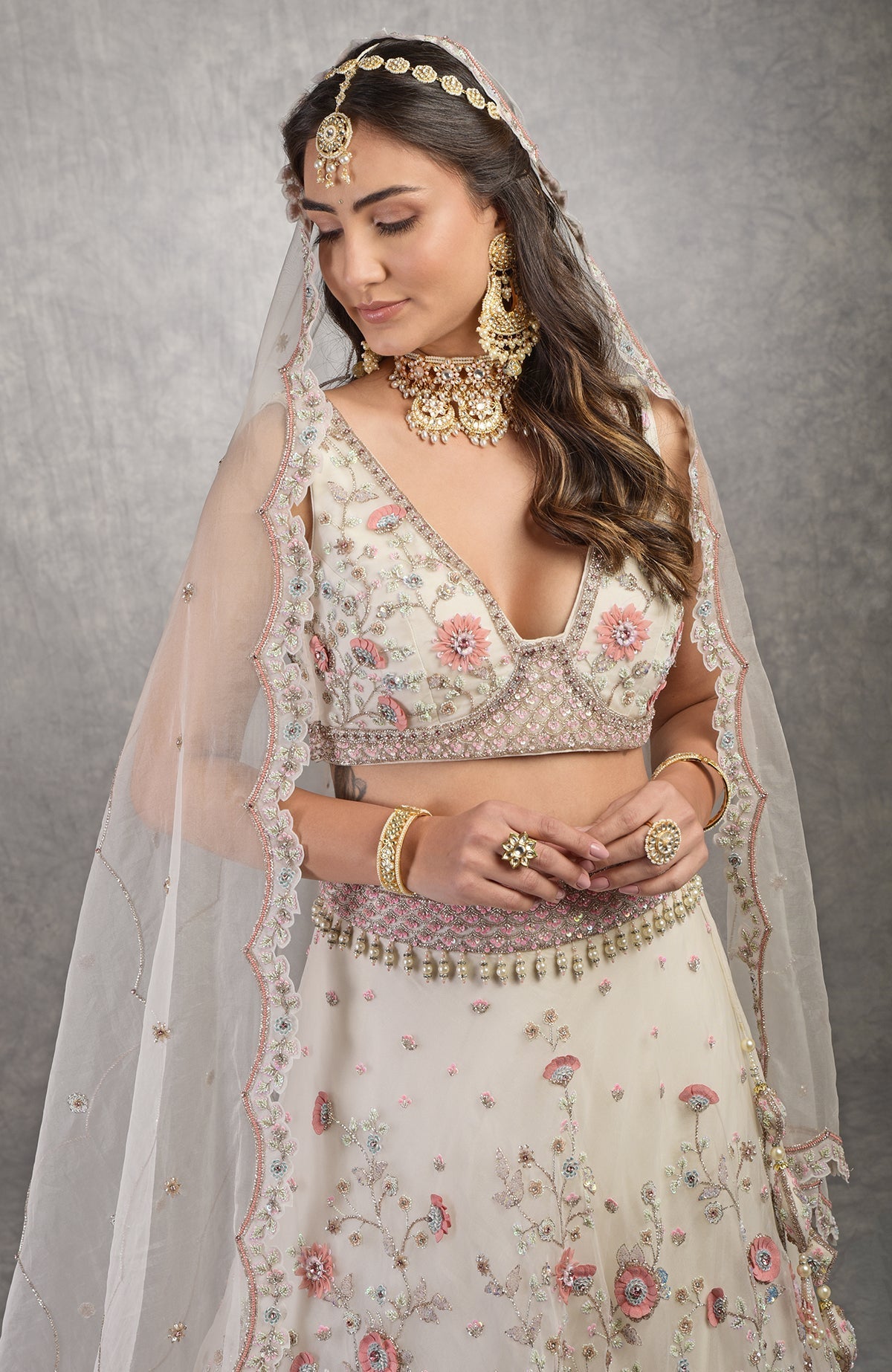 Off-white lehenga set with 3-D pink floral embroidery and crystal bead embellishments.
