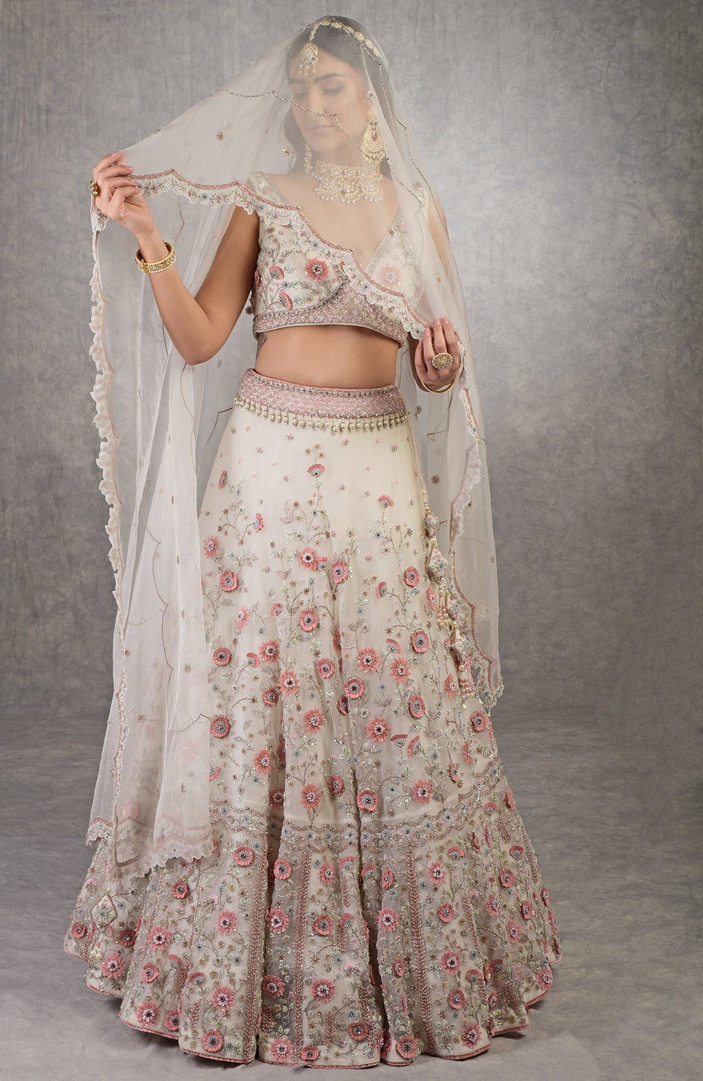 Off-white lehenga set with 3-D pink floral embroidery, crystal beadwork, and deep V-neck blouse.