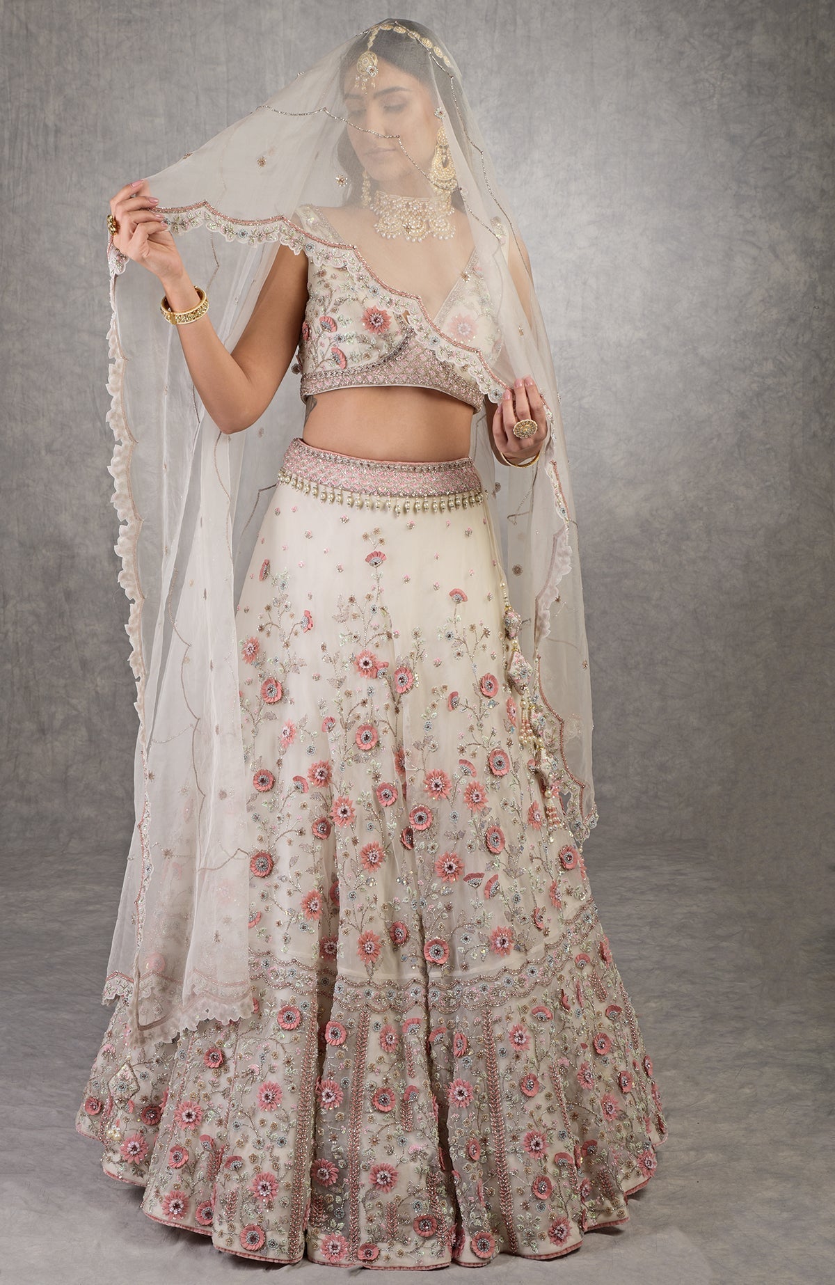 Off-white lehenga set with 3-D pink floral embroidery, crystal beadwork, and deep V-neck blouse.