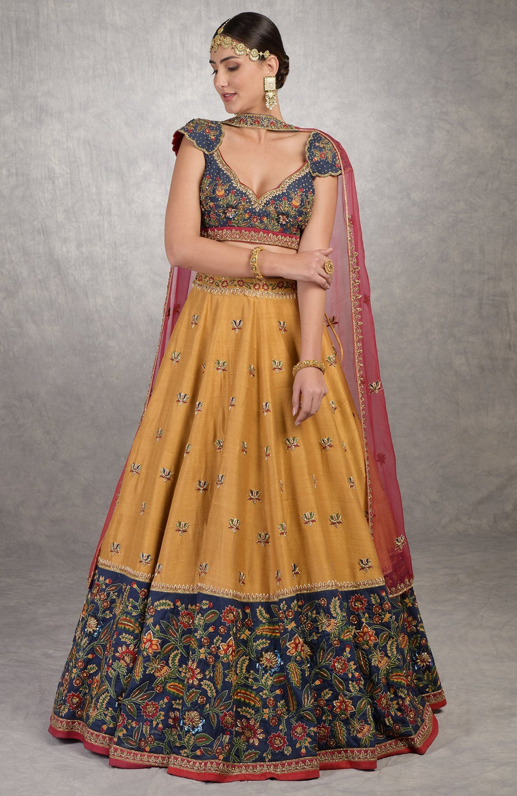 Classic blue lehenga with mustard embroidery, floral motifs, and red silk organza dupatta.