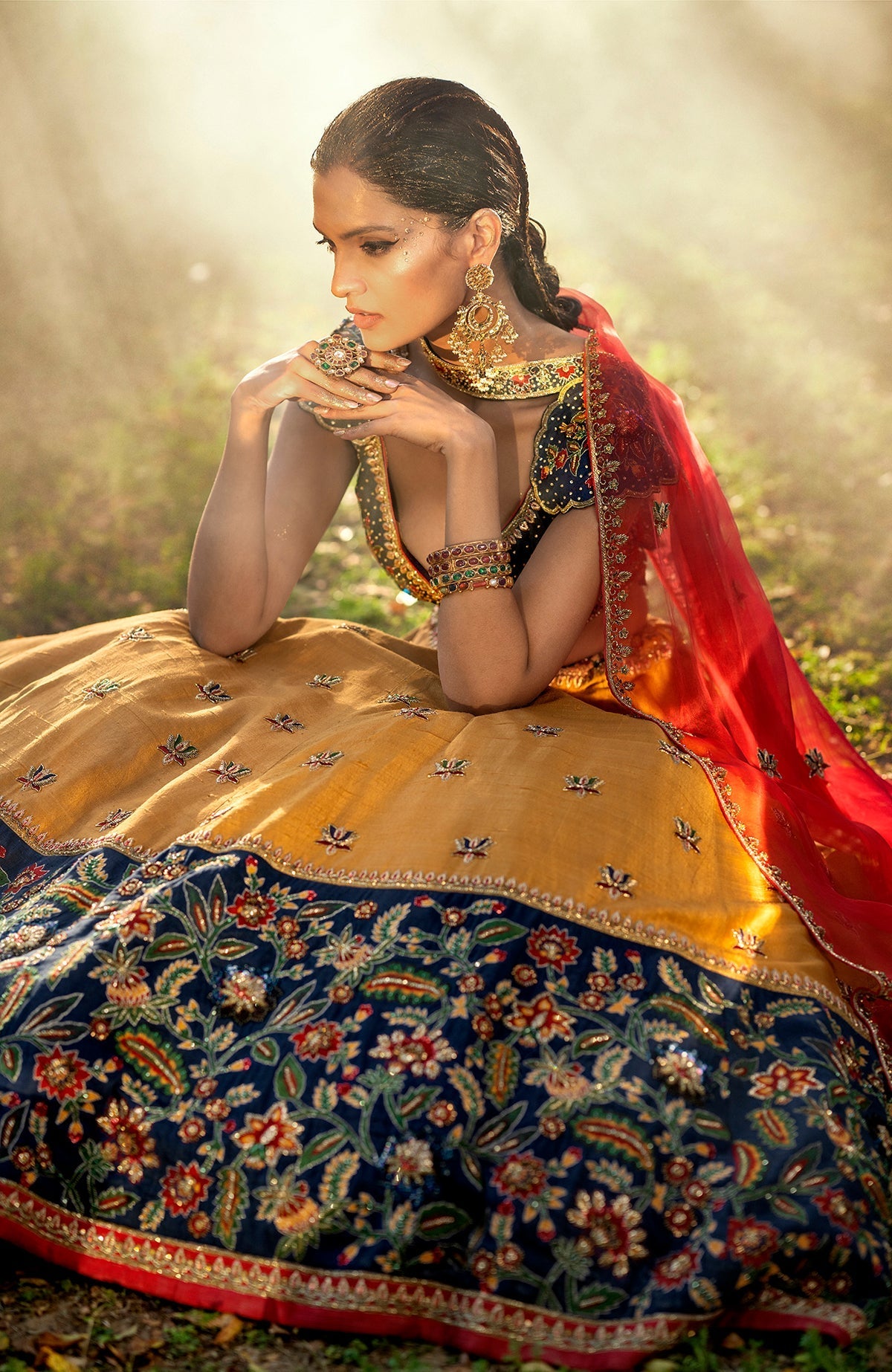 Classic blue lehenga with multicolor floral embroidery, gold zardozi, and red silk organza dupatta.