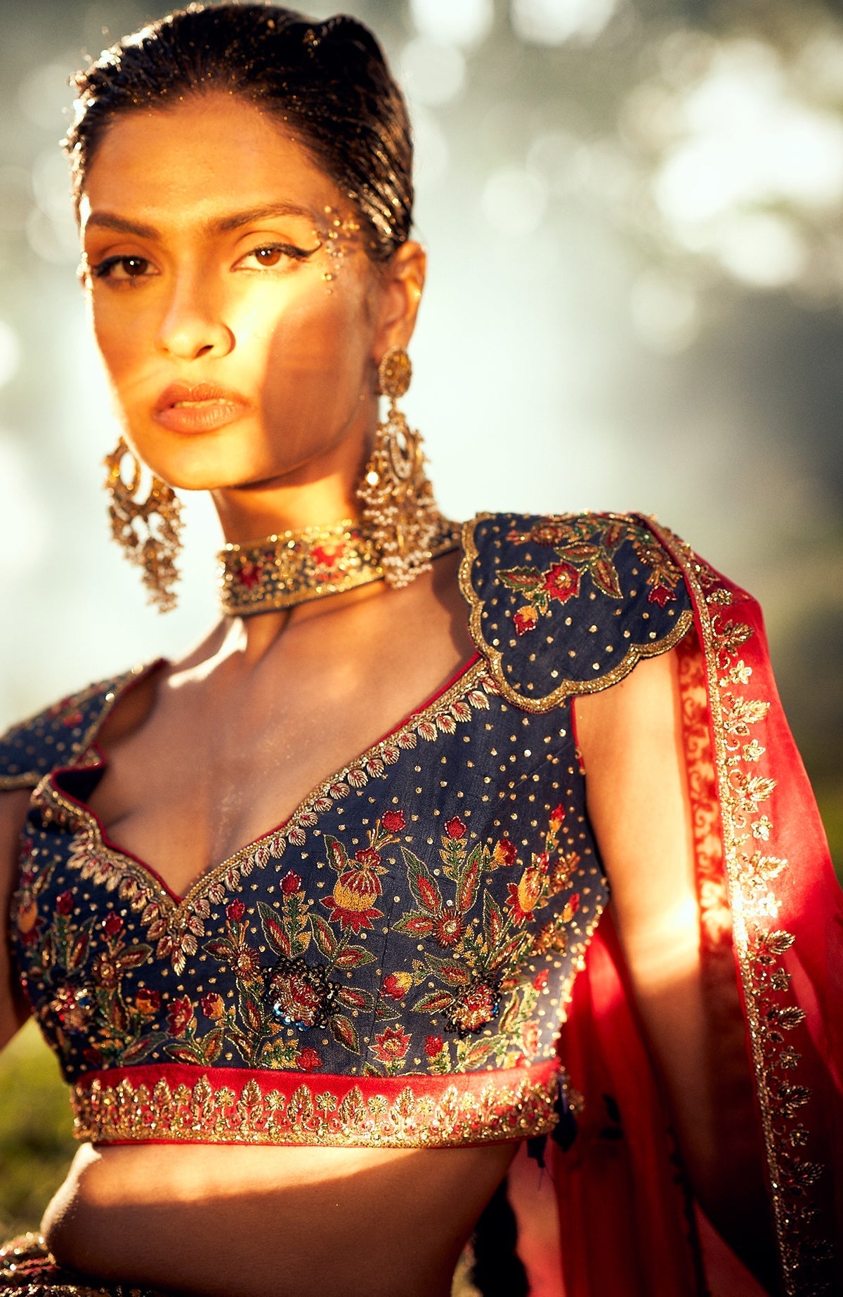 Classic blue lehenga with mustard floral embroidery, gold zardozi, and red silk organza dupatta.