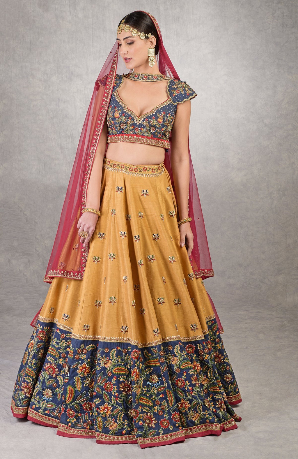 Classic blue lehenga with mustard embroidery, floral motifs, and red-yellow-green resham details.