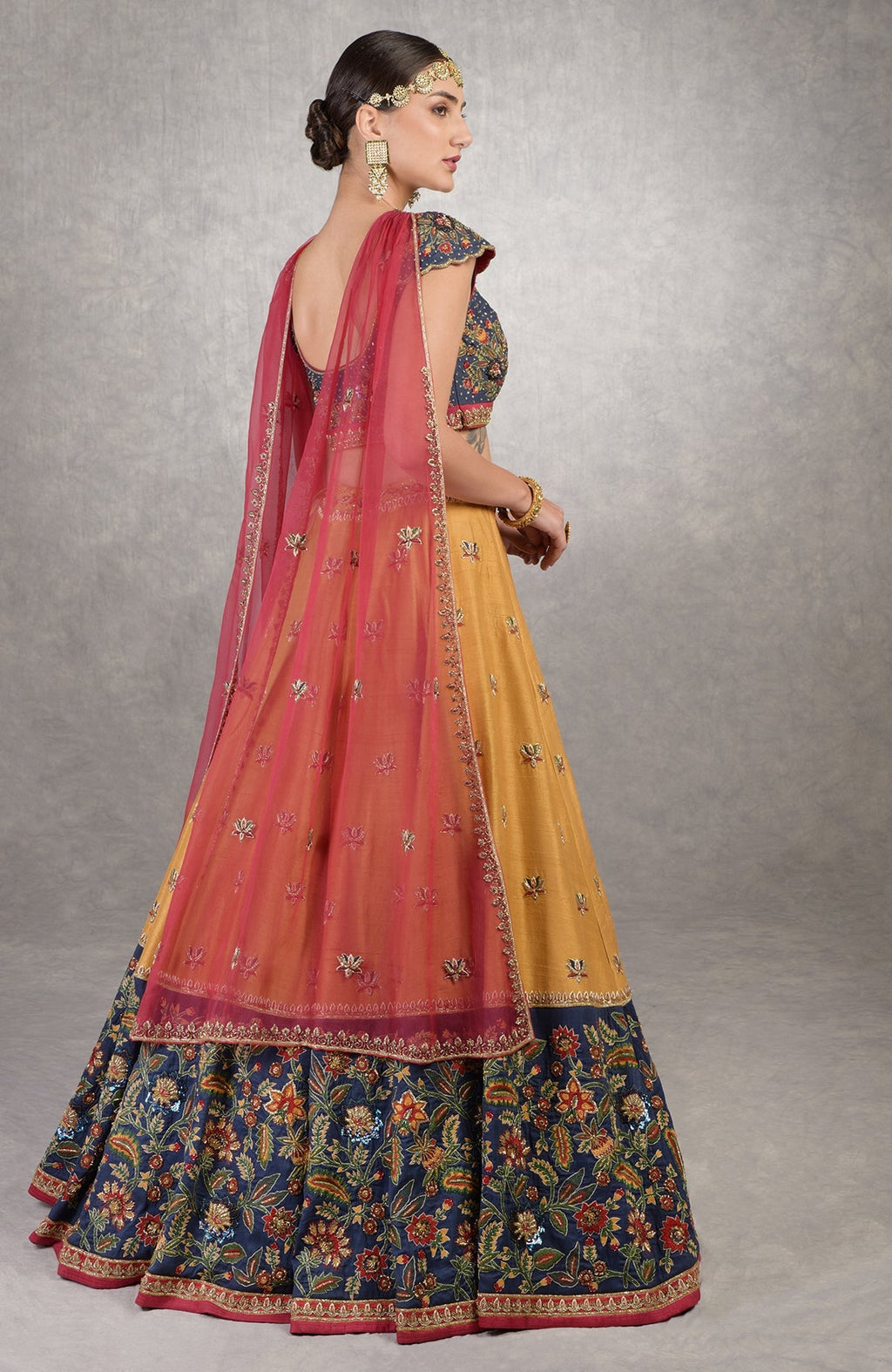 Classic blue lehenga with intricate floral embroidery, gold zardozi, and red-yellow-green accents.