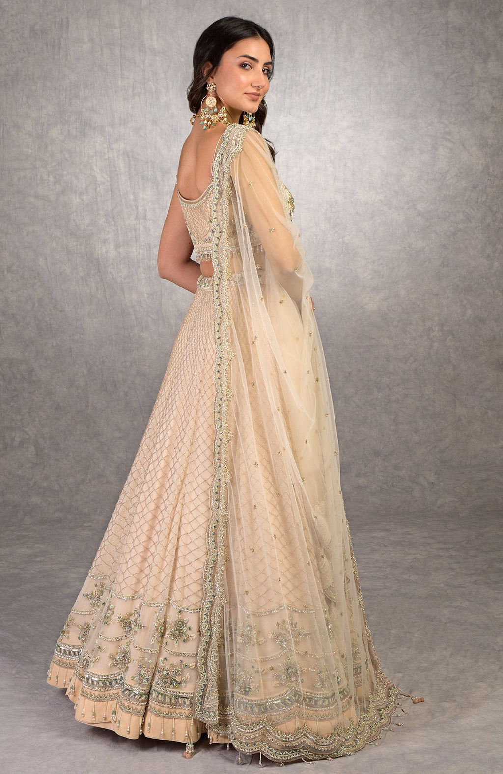 Champagne pink lehenga set with floral bead embroidery, scoop neck blouse, and scalloped tulle veil.