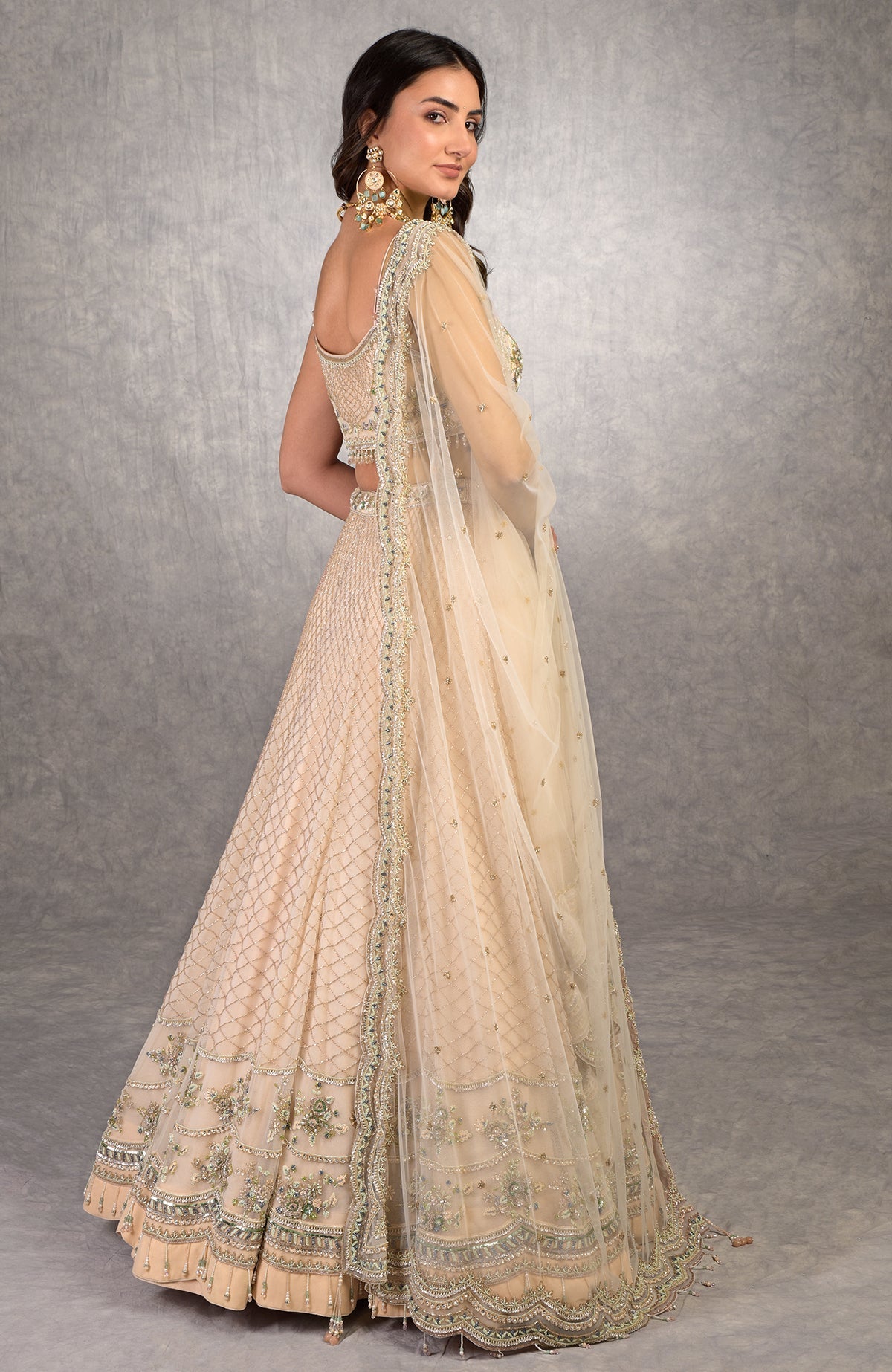 Champagne pink lehenga set with floral bead embroidery, scoop neck blouse, and scalloped tulle veil.