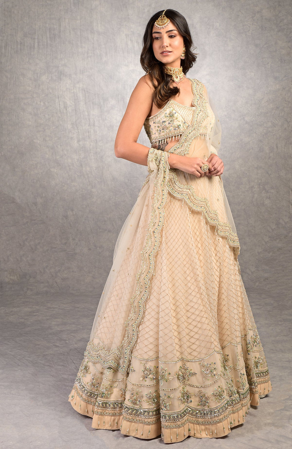 Champagne pink lehenga set with floral bead embroidery, scoop neck blouse, and scalloped tulle veil.