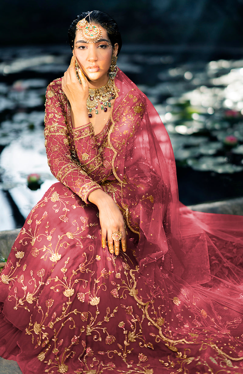 A model in a deep rosewood lehenga set with gold embroidery and a sheer dupatta.