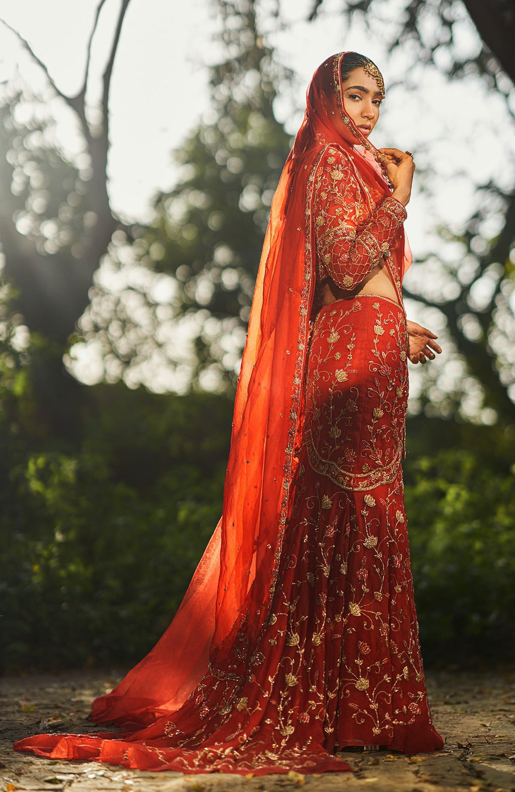 Red fish-cut lehenga set with hand-embroidered lotus motifs and sheer full-sleeve blouse.