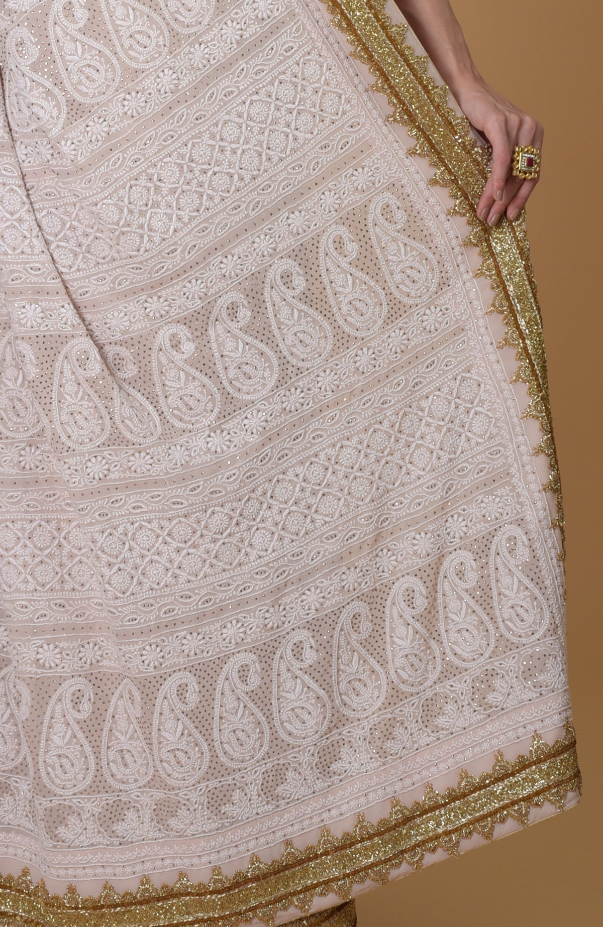 Nude pink Georgette saree with hand-embroidered Lucknowi Chikankari and gold zardozi details