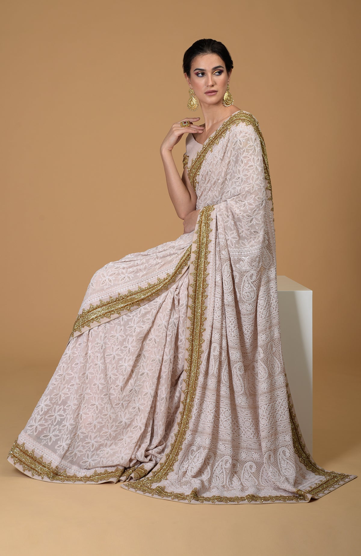 Nude pink Georgette saree with hand-embroidered Lucknowi Chikankari and gold zardozi details.