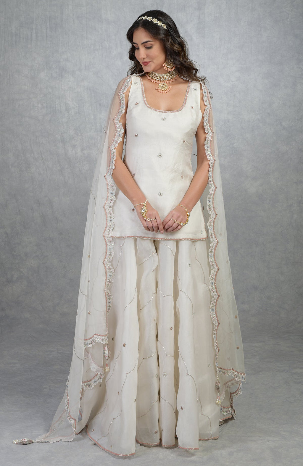 Off white silk organza sharara set with hand-embroidered floral beads, sequins, and scalloped edges.