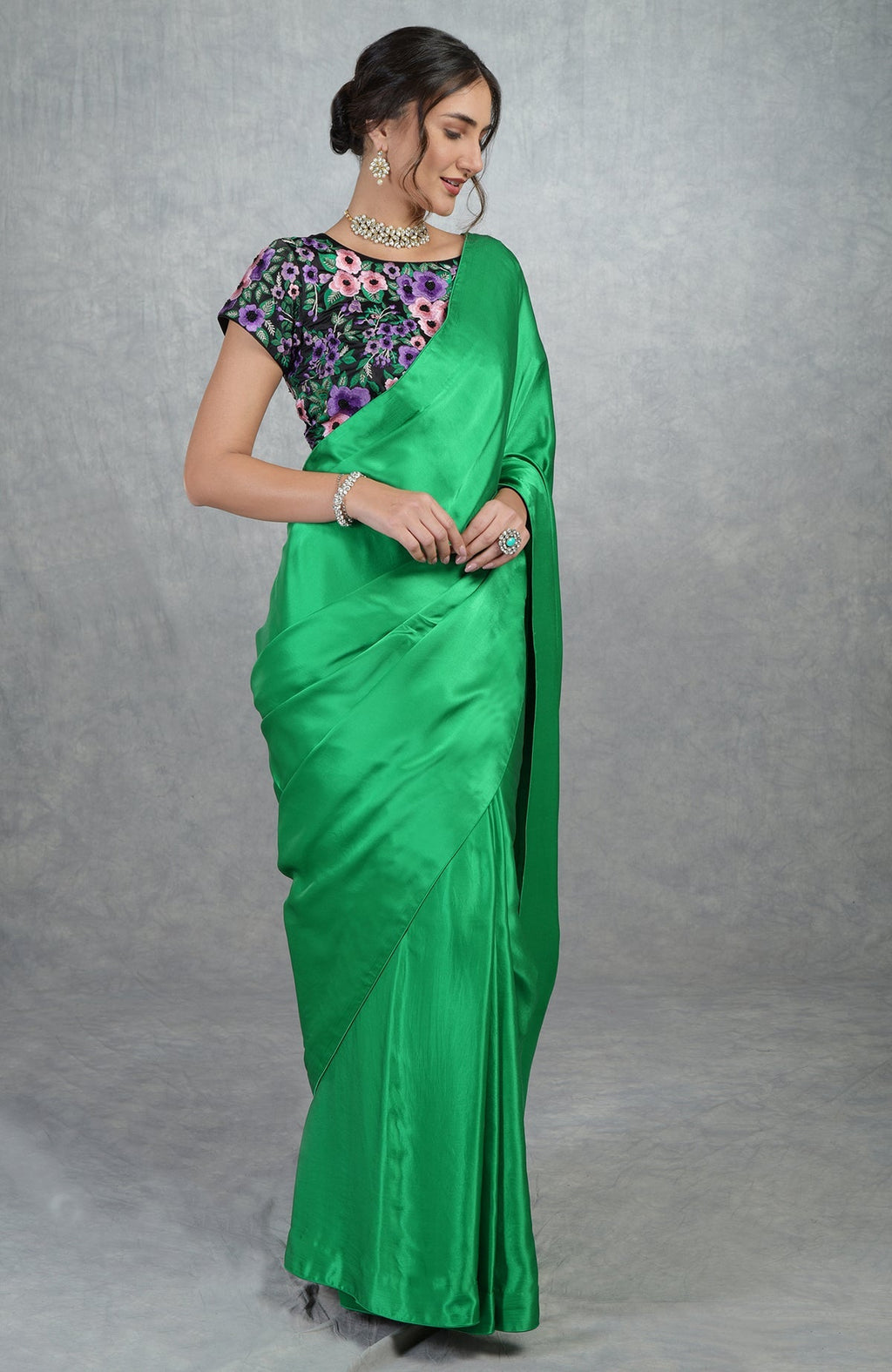 Emerald green satin silk saree with black floral embroidered blouse and cap sleeves.