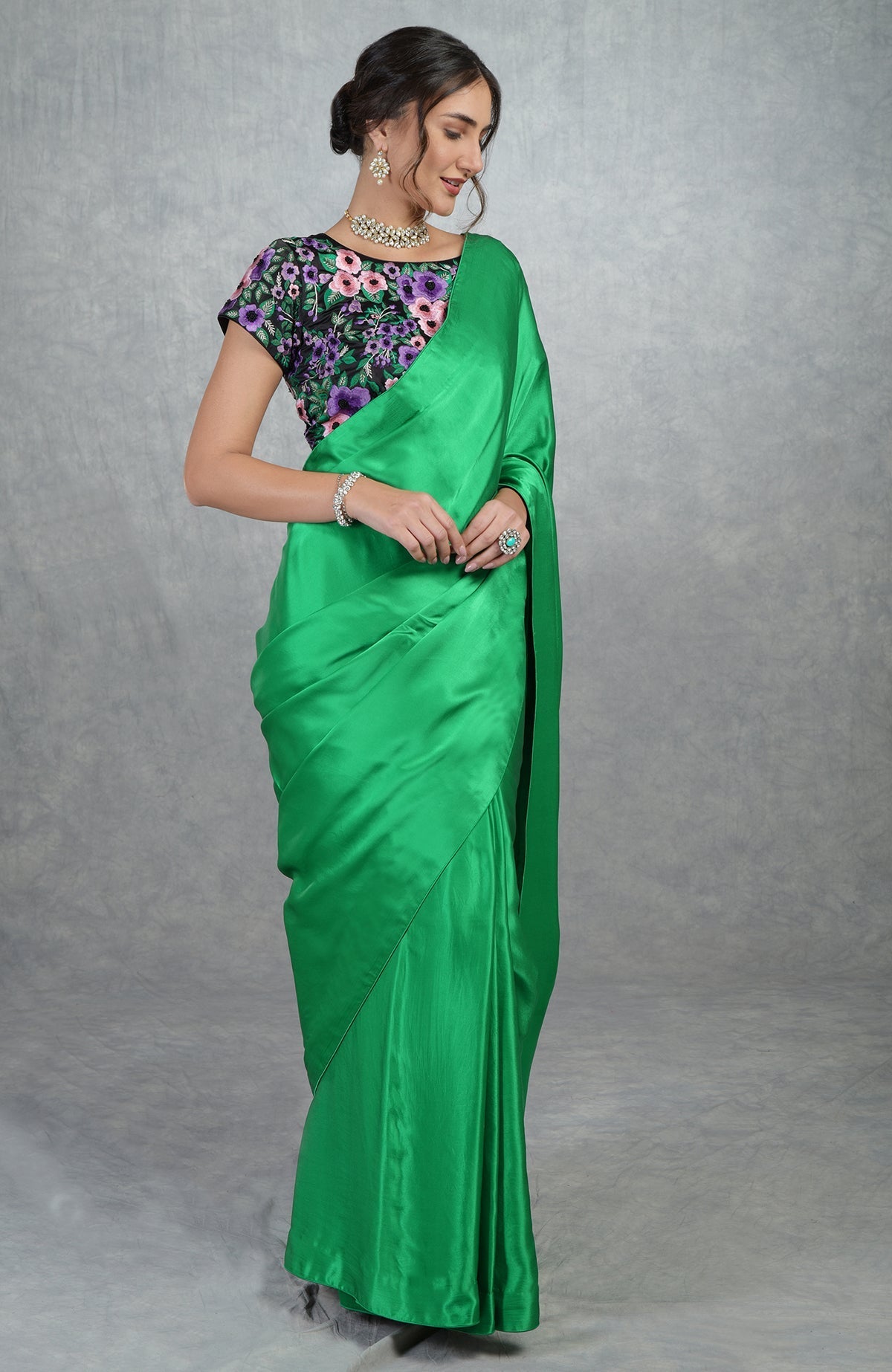 Emerald green satin silk saree with black floral embroidered blouse and cap sleeves.