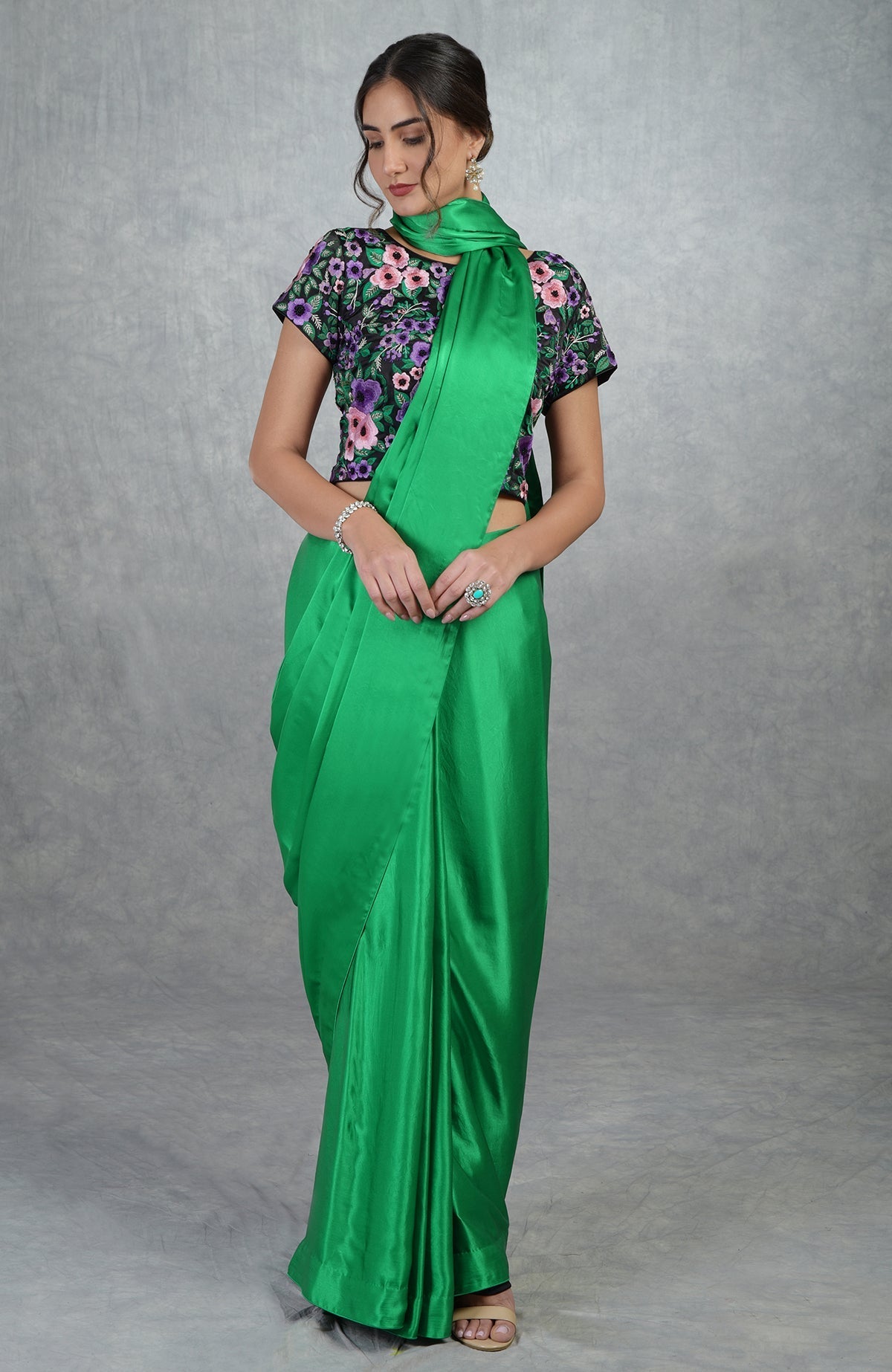 Emerald green satin silk saree with black floral embroidered blouse and cap sleeves.