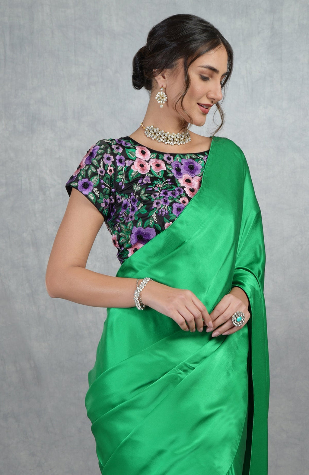 Emerald green satin silk saree with black satin blouse featuring multicolor floral embroidery and sequins