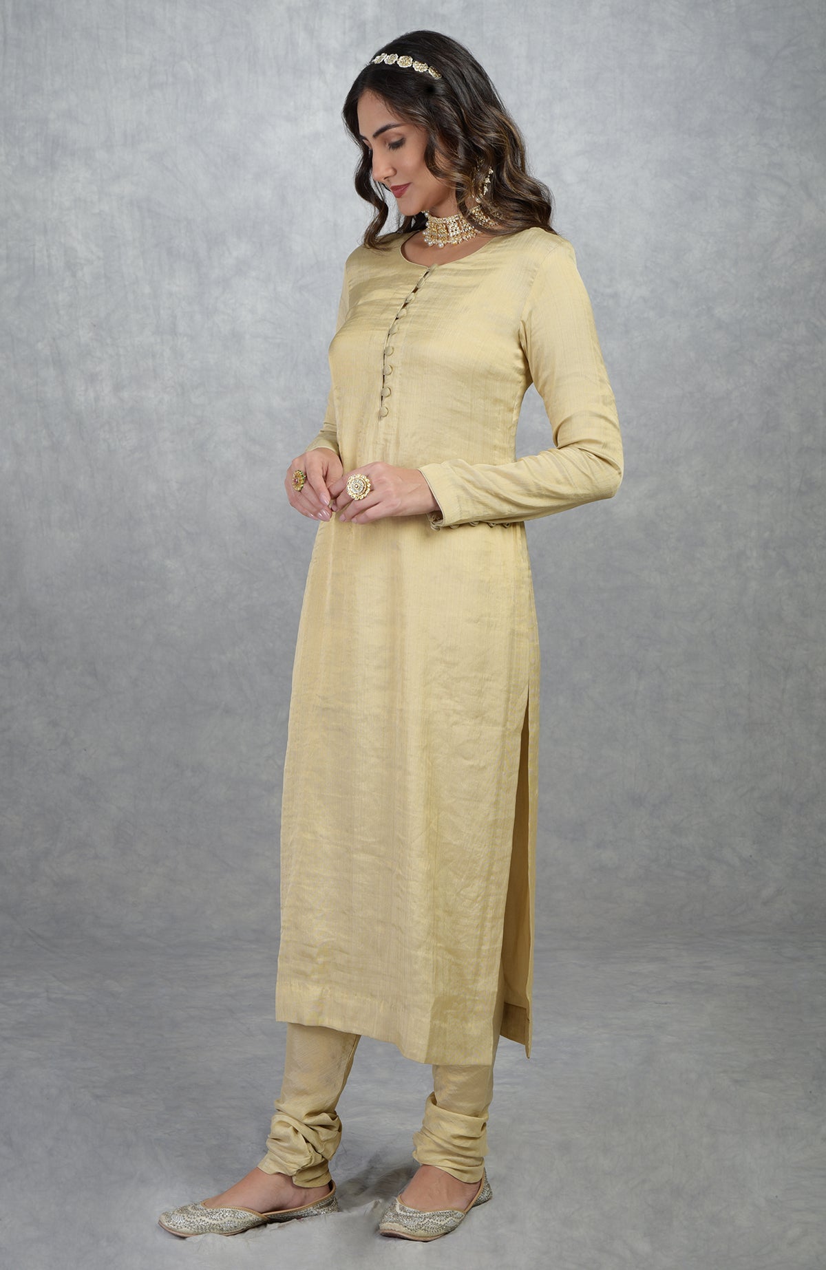 Gold tissue Banarasi kurta suit with round neck, long sleeves, and handcrafted button details.