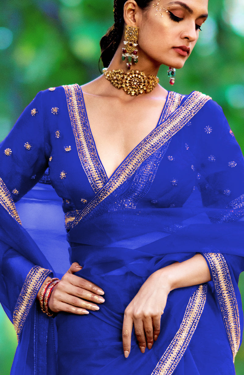 Royal blue organza silk saree with gold zari and crystal bead embroidery.