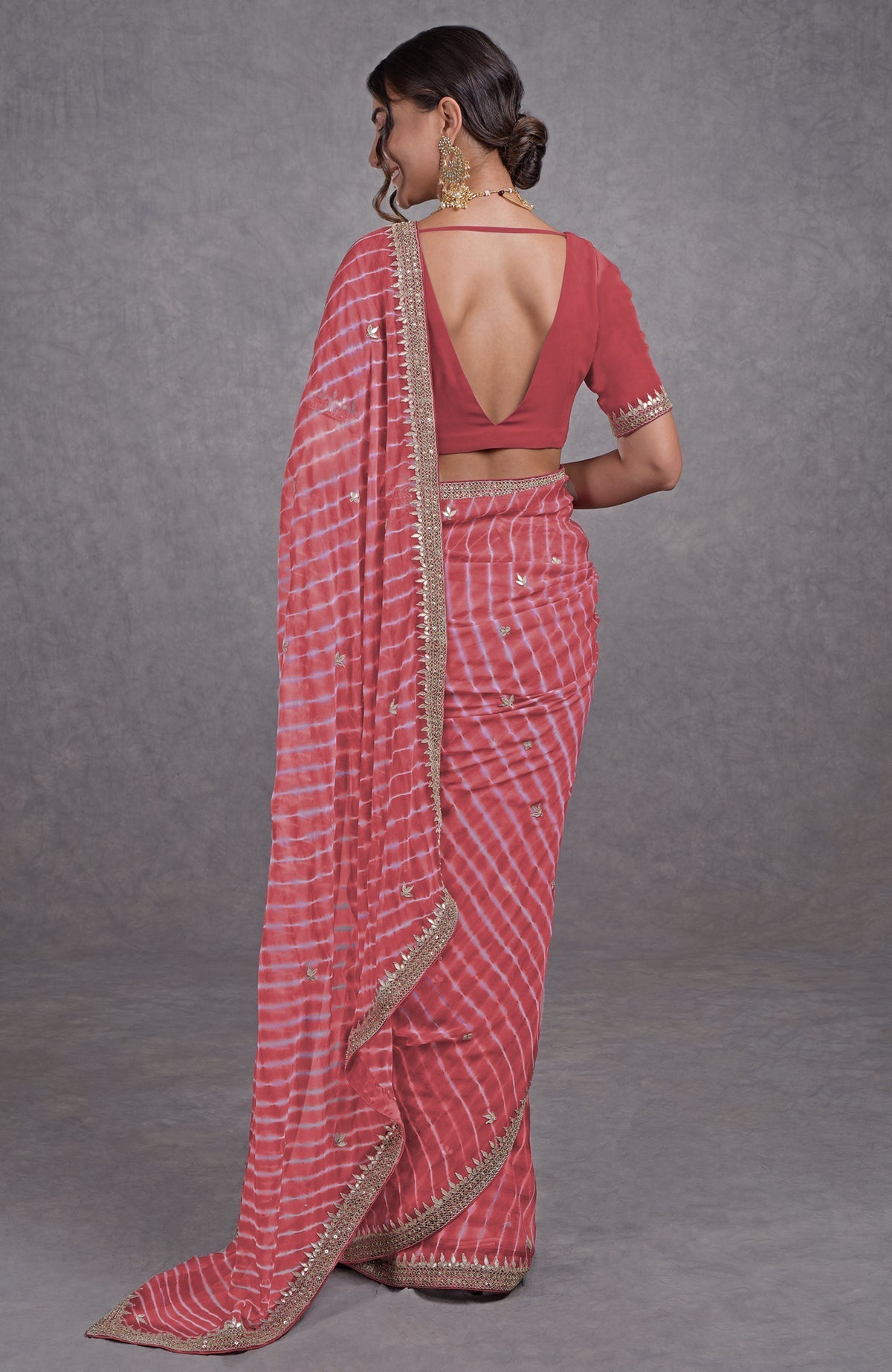 Woman in a garnet rose leheriya saree with rosegold marori-gota patti embroidery.