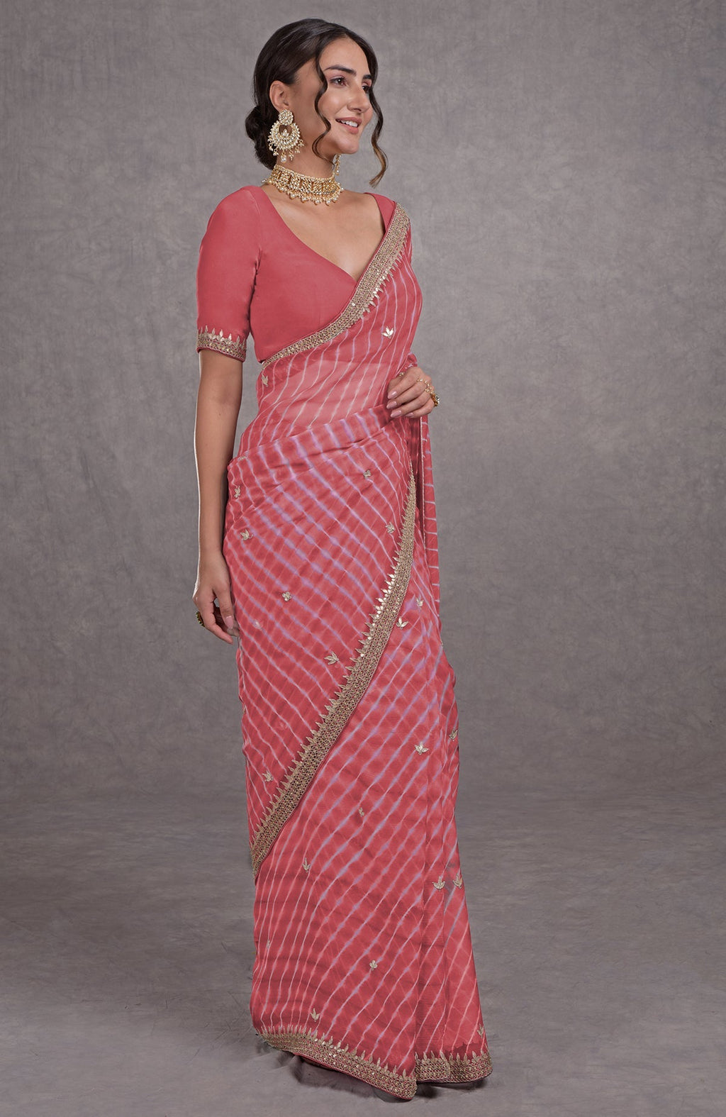 A woman models a garnet rose leheriya saree with rosegold marori-gota patti embroidery.