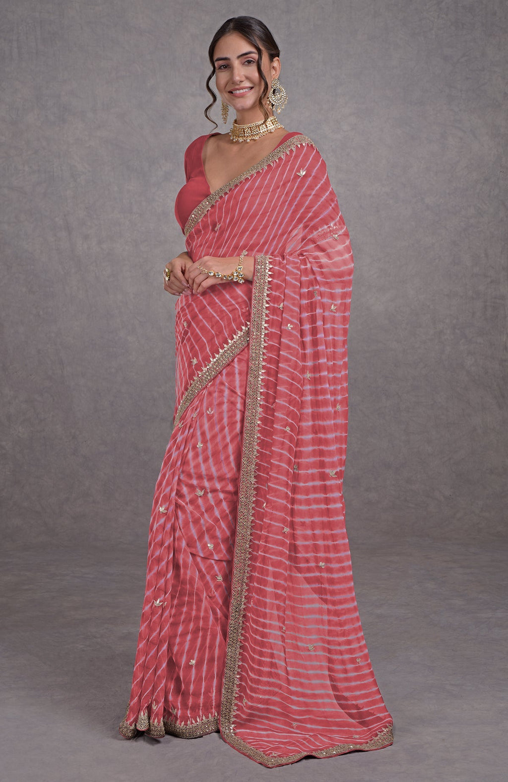 A woman in a garnet rose leheriya saree with rosegold marori-gota patti embroidery.