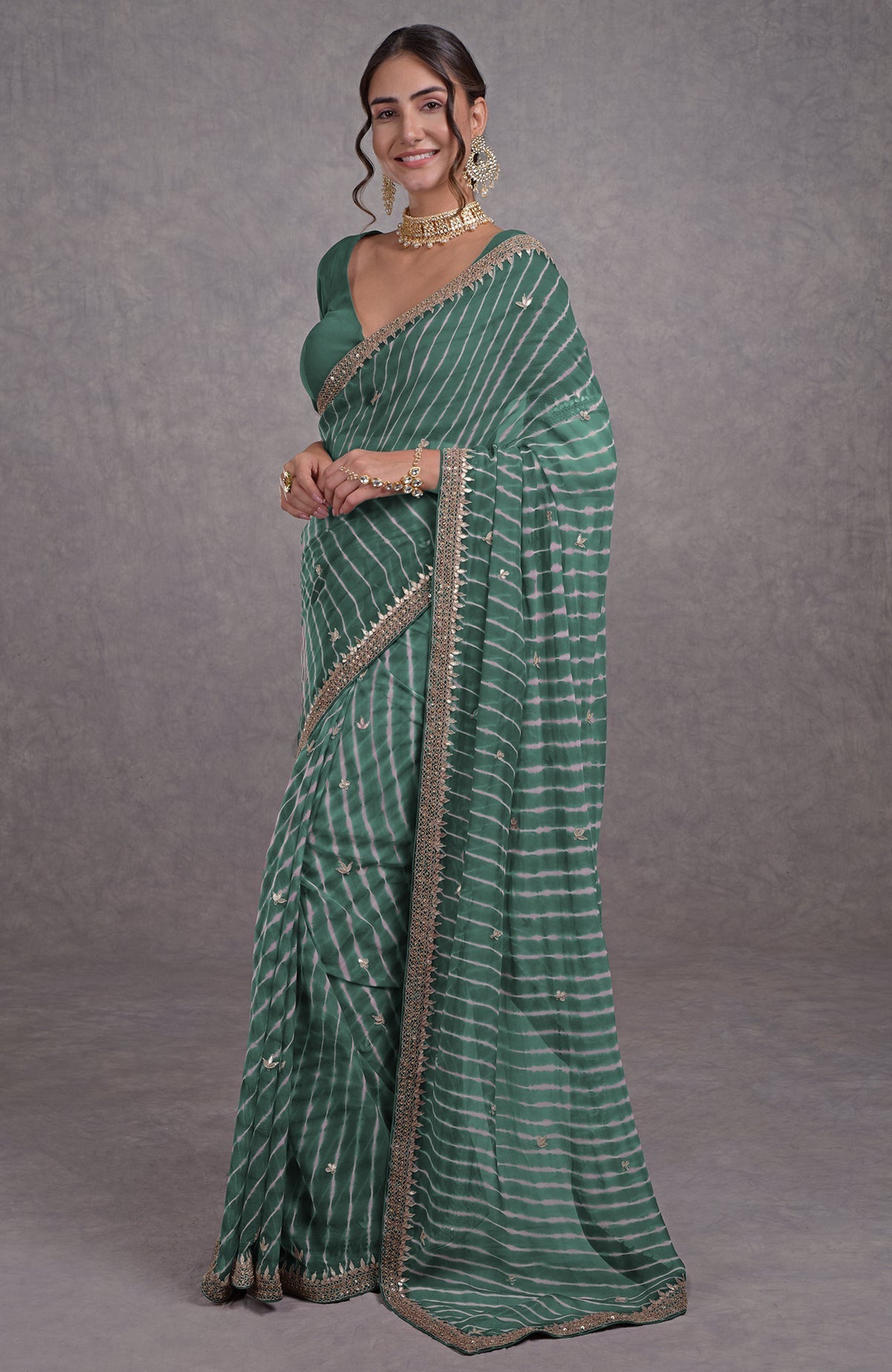 A woman models a jade leheriya saree with rose gold marori-gota patti embroidery.