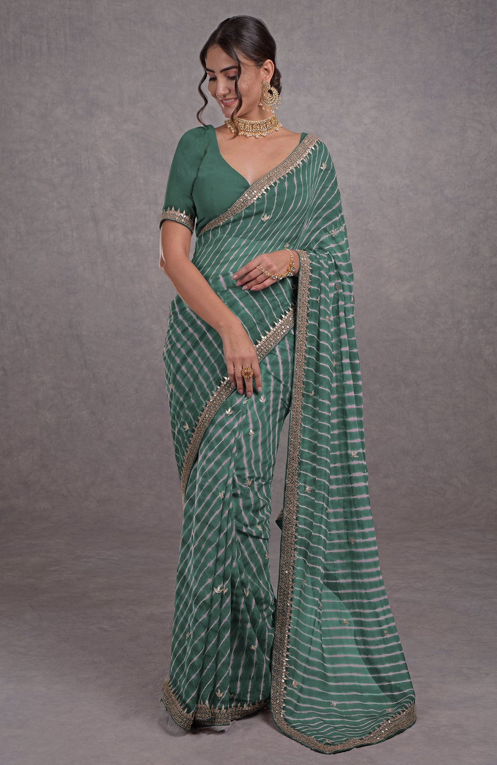 A woman models a jade green leheriya saree with rose gold marori-gota patti embroidery.