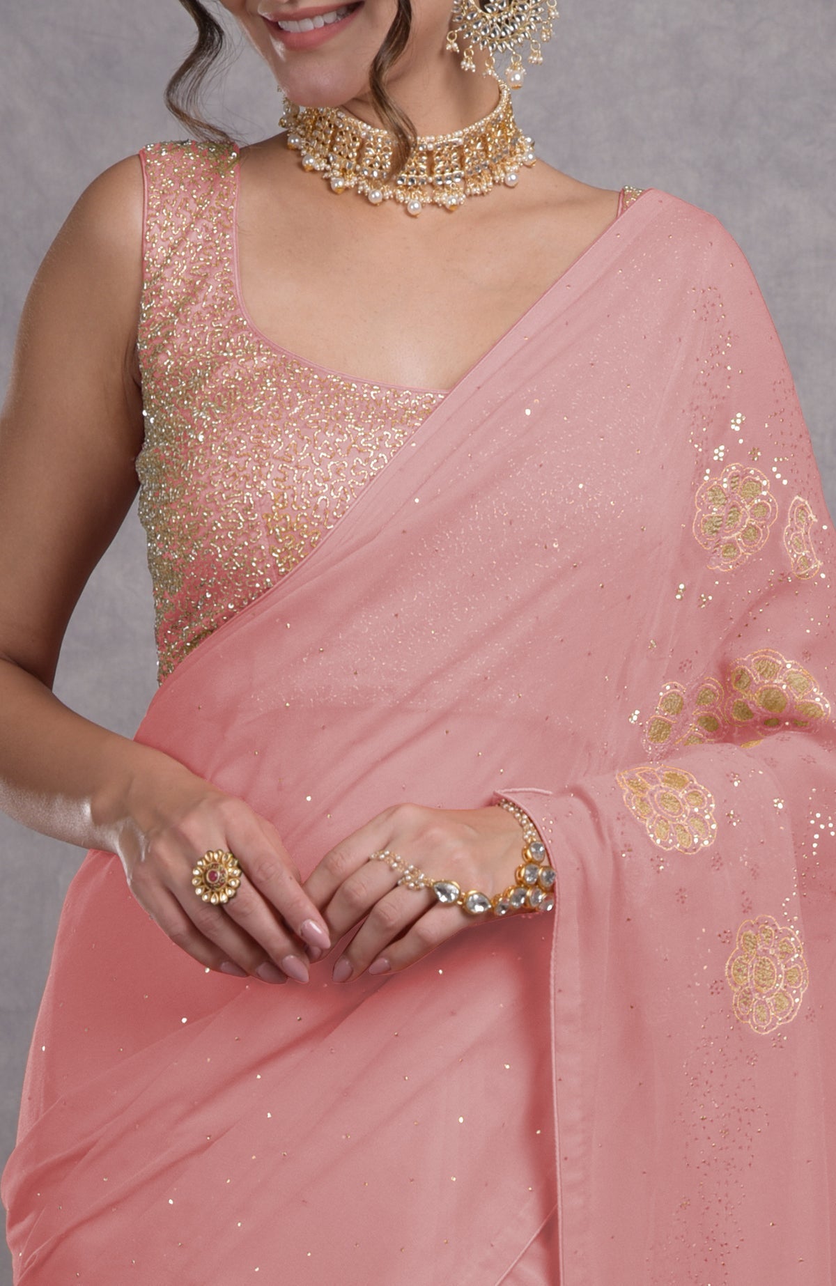 A woman in a pressed rose tissue cutwork hand embroidered mukaish saree.