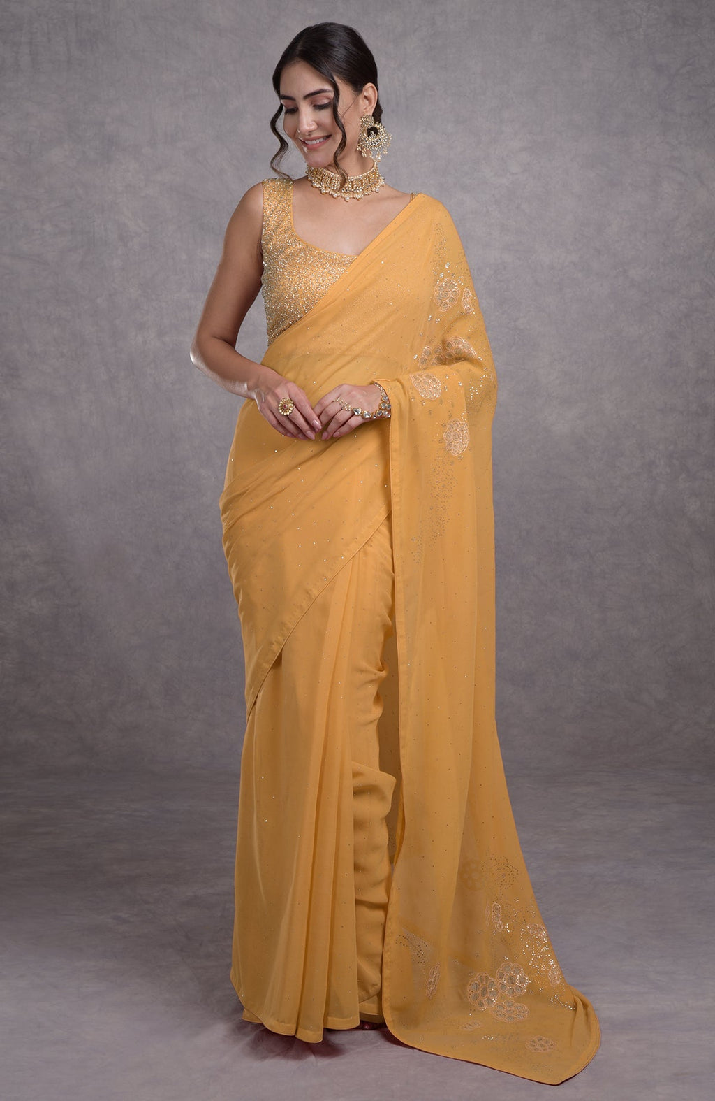A woman models a buff yellow saree with hand-embroidered mukaish and tissue cutwork flowers.