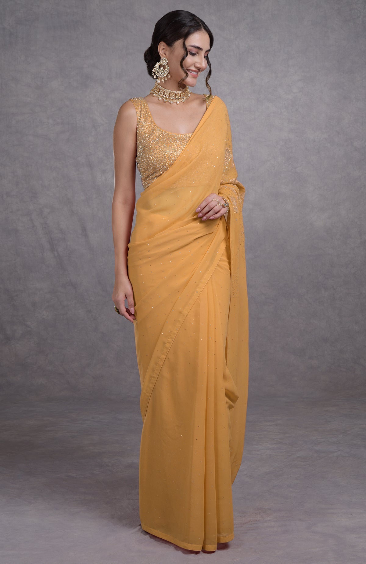 A woman models a buff yellow tissue cutwork hand-embroidered mukaish saree.