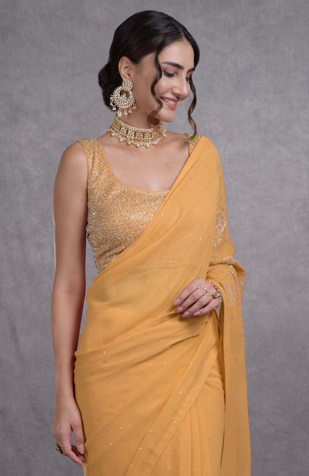 A woman models a buff yellow tissue cutwork hand-embroidered mukaish saree with a matching blouse.