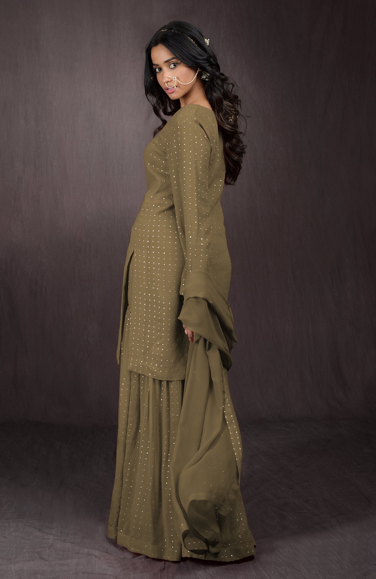 An olive gold embellished sharara set with a woman posing.