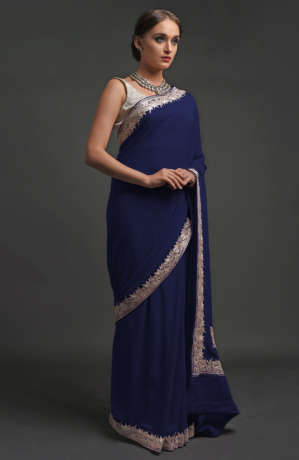 A woman models a navy blue georgette saree with silver tilla lotus embroidery.