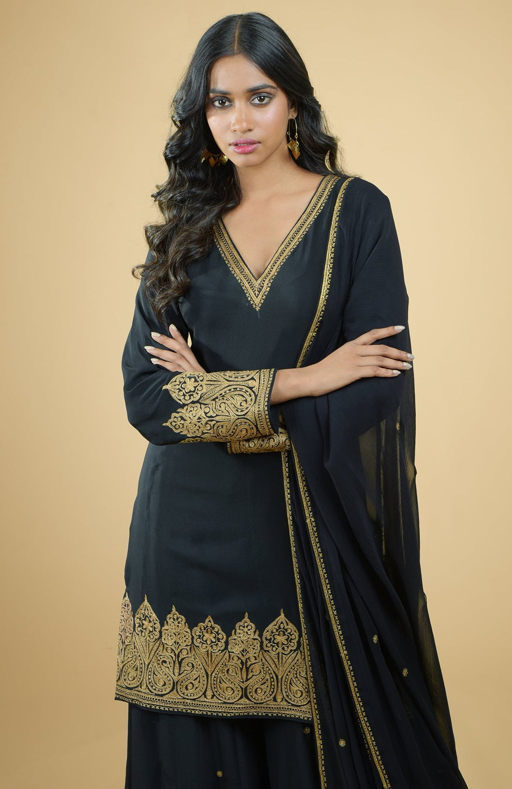 Black sharara set with gold Kashmiri Tilla Aari floral and paisley embroidery on kurta and dupatta.