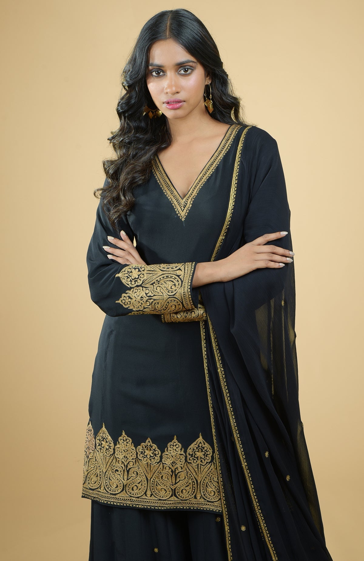 Black sharara set with gold Kashmiri Tilla Aari floral and paisley embroidery on kurta and dupatta.