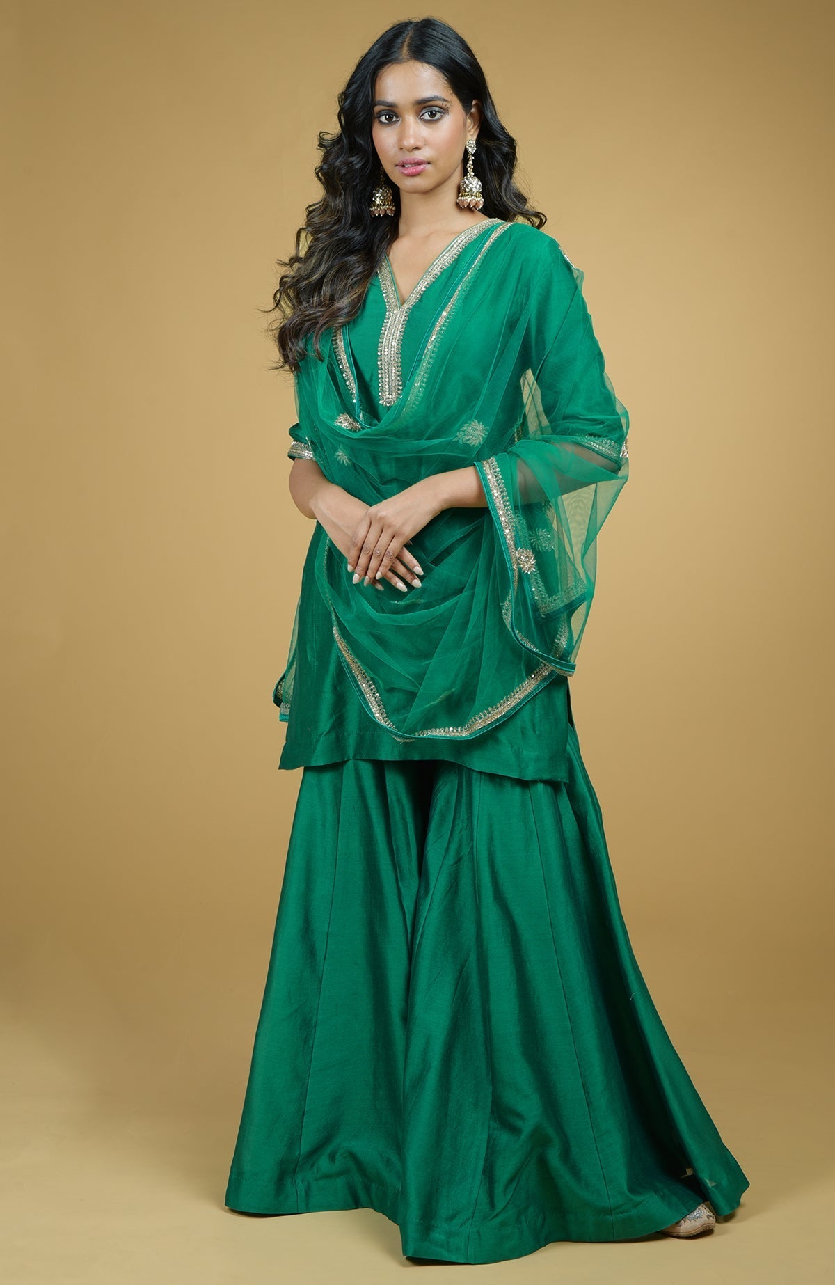 Emerald green chanderi silk Gharara set with gold hand-embroidered zardozi floral work and net dupatta.