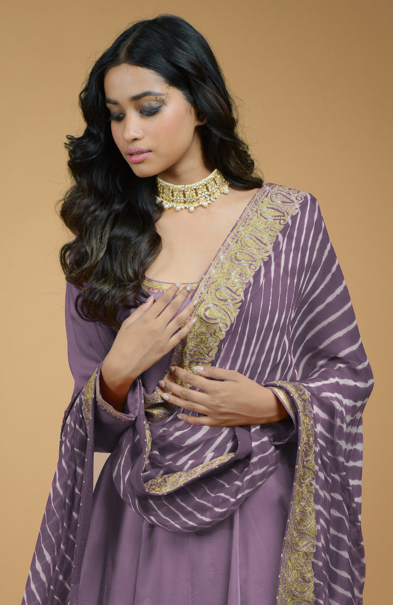 A woman in a lavender Anarkali set with a leheriya-tilla embroidered dupatta and a choker necklace.