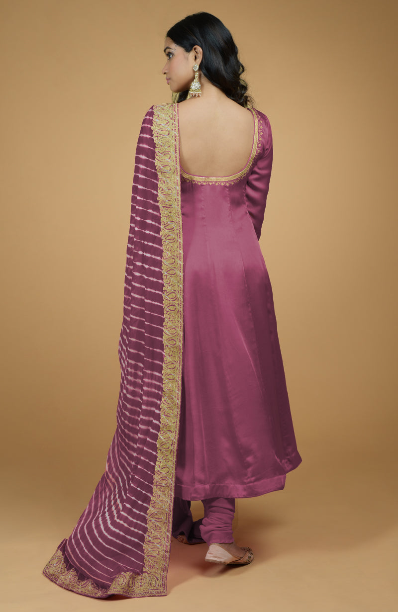 A woman from behind wears a mauve Anarkali set with a striped dupatta.