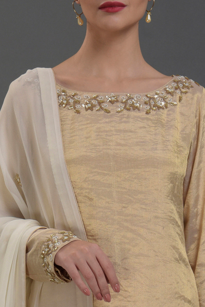 Ivory-gold silk tissue kurta with chikankari and zardozi embroidery paired with georgette sharara and dupatta.