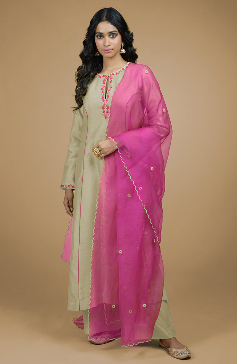 A woman models a beige kurta set with a magenta organza dupatta.